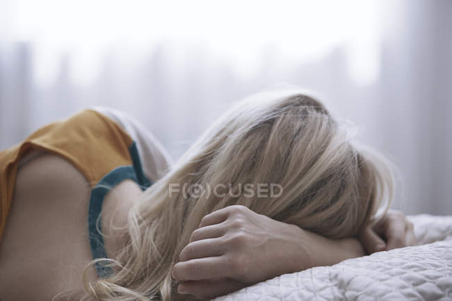 Femme blonde allongée sur le lit — Photo de stock