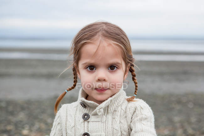 Portrait of serious girl with braided pigtails on beach — Stock Photo