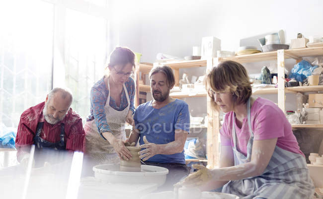 Mature adults using pottery wheels in studio — Stock Photo