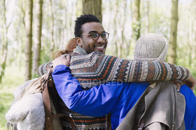 Retrato sorridente homem abraçando amigos caminhadas na floresta — Fotografia de Stock