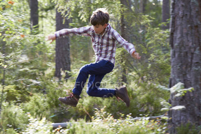 Энергичный мальчик, прыгающий в лесу — стоковое фото