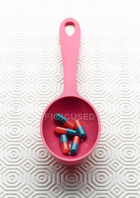 Capsule mediche in cucchiaio rosa — Foto stock