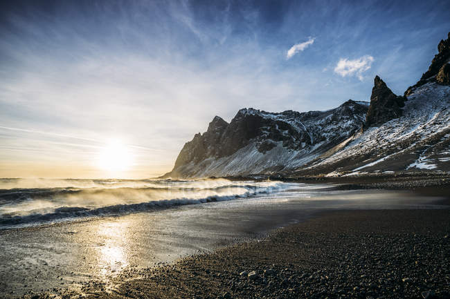 Sole che tramonta su spiaggia tranquilla e montagna innevata, Islanda — Foto stock