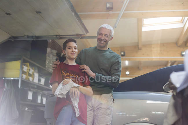 Portrait smiling father and son rebuilding classic car — Stock Photo