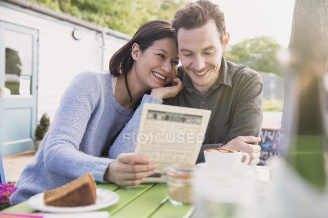 Улыбающаяся пара смотрит меню в кафе на открытом воздухе — стоковое фото