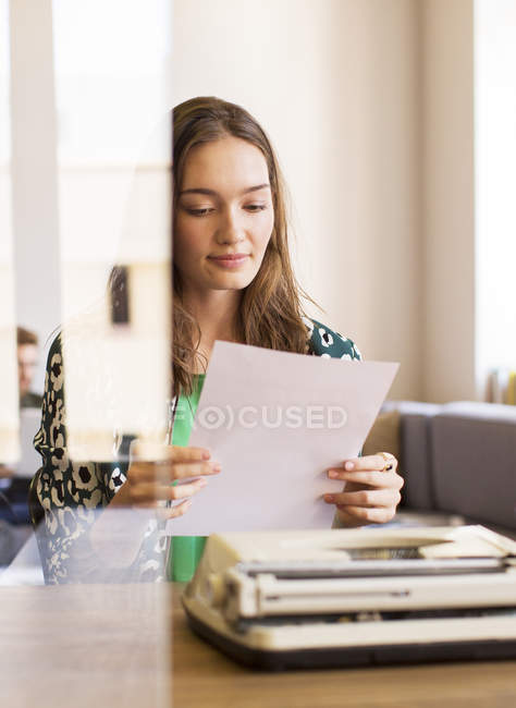 Kreative Geschäftsfrau überprüft Papierkram an Schreibmaschine im Büro — Stockfoto