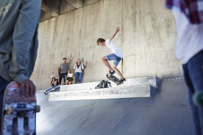 Amigos assistindo e torcendo adolescente skate no parque de skate — Fotografia de Stock