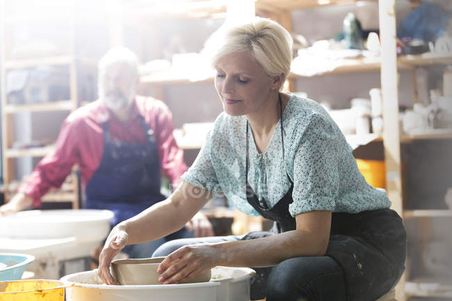 Mature woman using pottery wheel in studio — Stock Photo