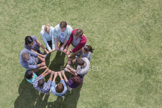 Equipe conectada em círculo em torno de aro de plástico no campo — Fotografia de Stock