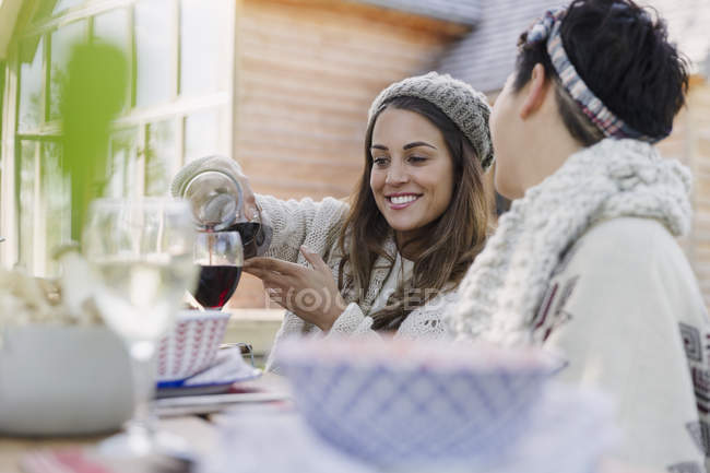 Amis verser du vin à la table de déjeuner patio — Photo de stock