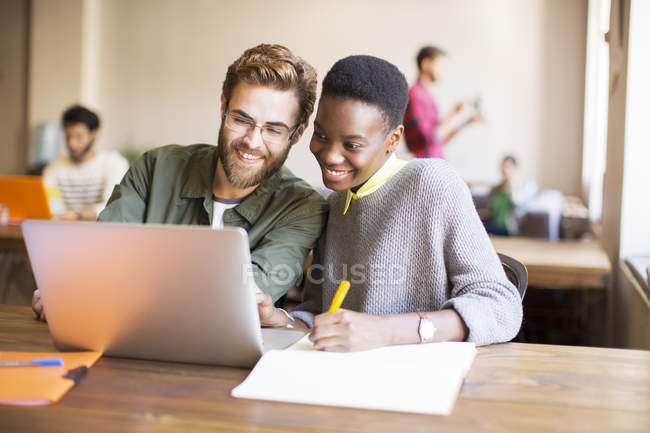 Des gens d'affaires créatifs souriants utilisant un ordinateur portable et un remue-méninges — Photo de stock