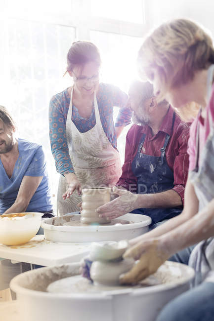 Teacher guiding mature students at pottery wheels in studio — Stock Photo