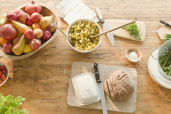 Паста с видом сверху, фрукты и хлеб на обеденном столе — стоковое фото