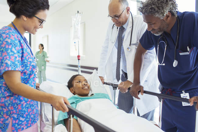 Врачи и медсестра разговаривают с пациентом на носилках в коридоре больницы — стоковое фото