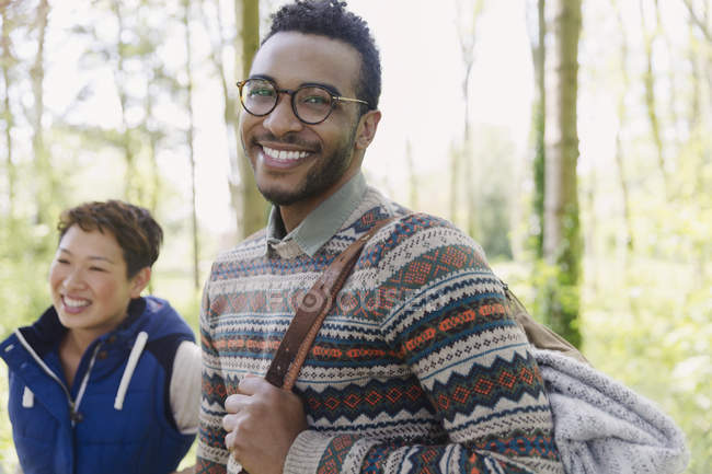 Portrait smiling man with backpack hiking in woods — Stock Photo