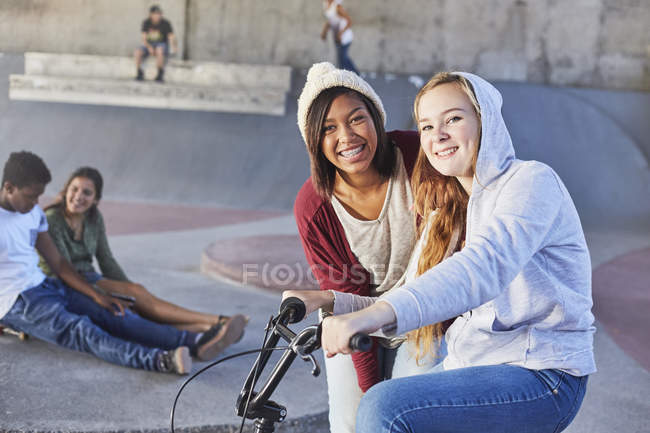 Portrait smiling teenage girls with BMX bicycle at skate park — Stock Photo