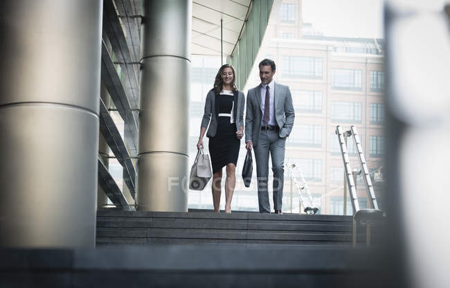 Corporate businessman and businesswoman descending stairs outdoors — Stock Photo