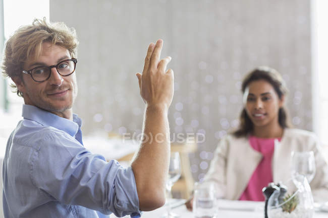 Hombre haciendo gestos para el servicio en la mesa del restaurante - foto de stock