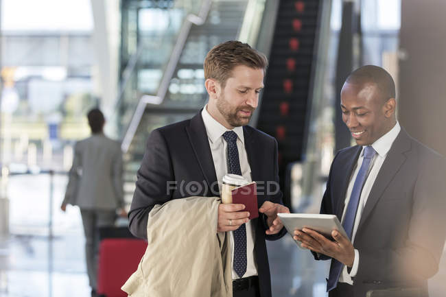 Hommes d'affaires avec tablette numérique parlant à l'aéroport — Photo de stock