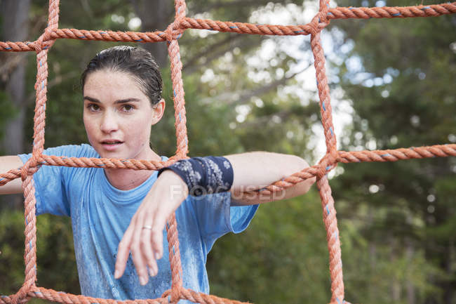 Portrait of confident woman leaning on net at boot camp — Stock Photo