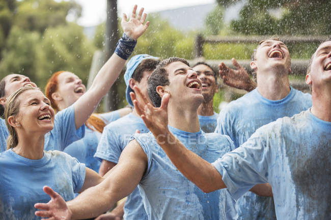 Equipe entusiasmada desfrutando de chuva no acampamento de inicialização — Fotografia de Stock