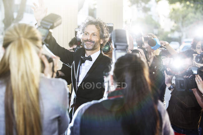 Celebridad saludando a los fotógrafos paparazzi en el evento - foto de stock