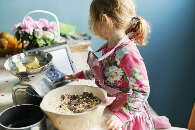 Chica con tableta digital hornear en la cocina - foto de stock