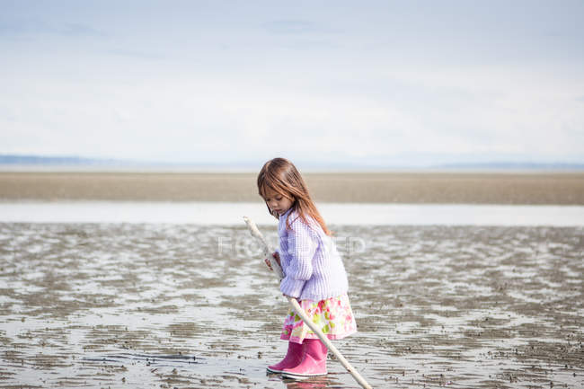 Ragazza con bastone giocare sulla spiaggia — Foto stock