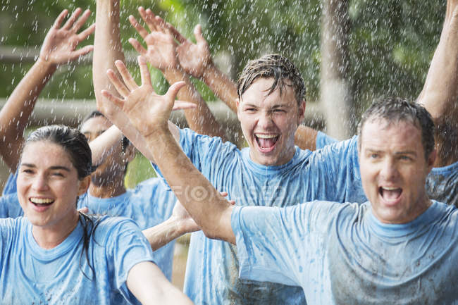 Enthusiastic team cheering in rain at boot camp — Stock Photo