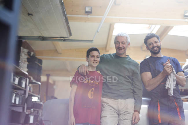 Retrato sonriente familia mecánica en taller de reparación de automóviles - foto de stock