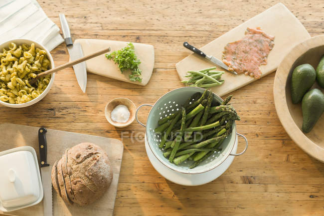 Overhead lox vista, espargos, massas, pão e manteiga na mesa de jantar — Fotografia de Stock