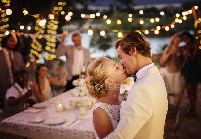 Молода пара цілується під час весільного прийому в домашньому саду — стокове фото