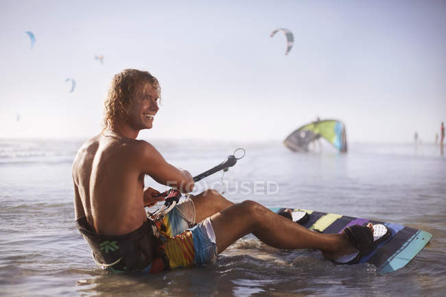 Sorrindo homem pronto para kiteboard na praia — Fotografia de Stock
