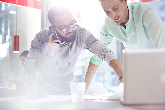Creative businessmen reviewing blueprints in modern cafe — Stock Photo