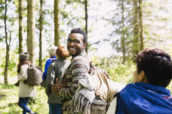 Портрет усміхненого чоловіка з рюкзаком, що йде в сонячному лісі — стокове фото