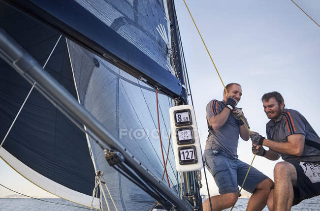 Uomini vela tirando attrezzature sartiame su barca a vela — Foto stock