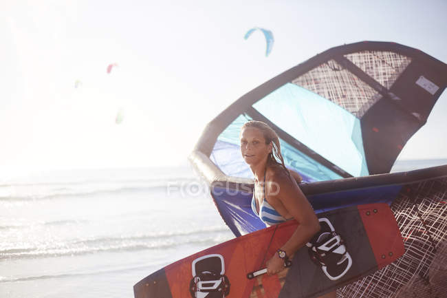 Mulher retrato carregando equipamento kiteboard na praia — Fotografia de Stock