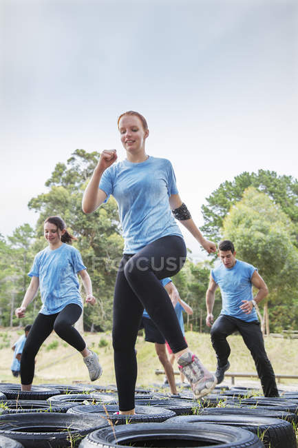 Determined woman jumping tires on boot camp obstacle course — Stock Photo