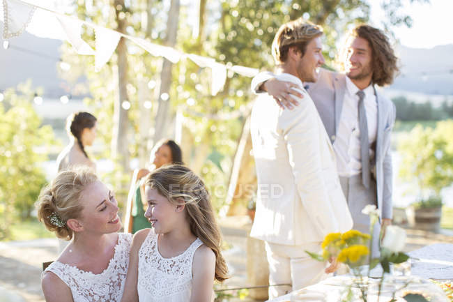 Невеста разговаривает с подружкой невесты во время свадебного приема в саду — стоковое фото