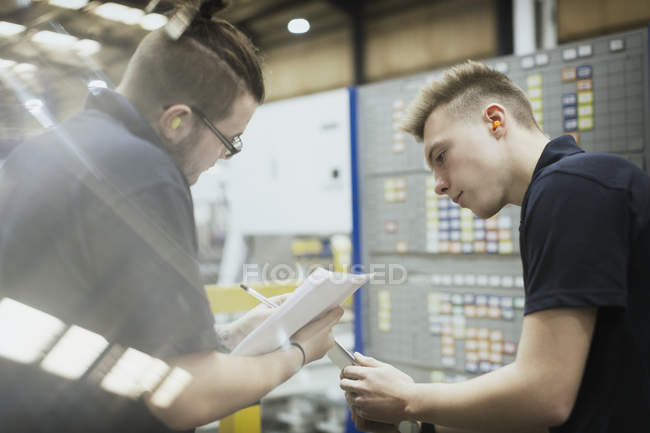 Trabajadores reunidos con papeleo en fábrica de acero - foto de stock