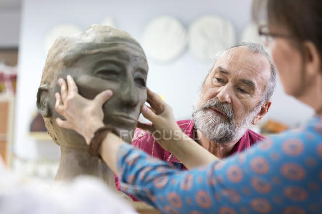 Woman sculpting clay face in pottery studio — Stock Photo