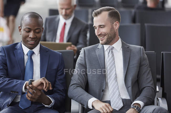 Businessmen checking the time on wristwatch in airport departure area — Stock Photo
