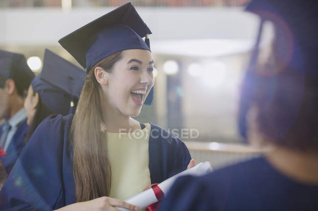 Enthousiaste diplômée du collège féminin en casquette et robe — Photo de stock