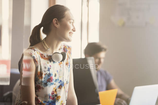 Empresária sorridente com fones de ouvido no escritório moderno — Fotografia de Stock
