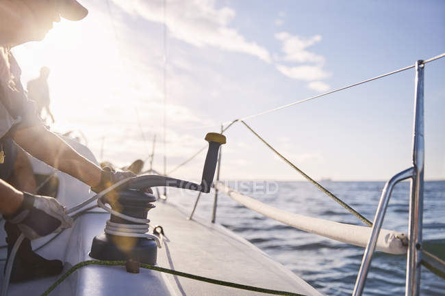 Чоловік регулює вітрильну лебідку на вітрильному човні — стокове фото