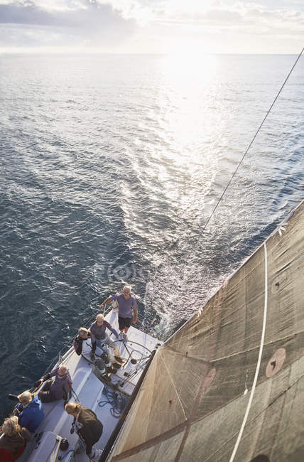 Друзья, плывущие на паруснике в солнечном океане — стоковое фото