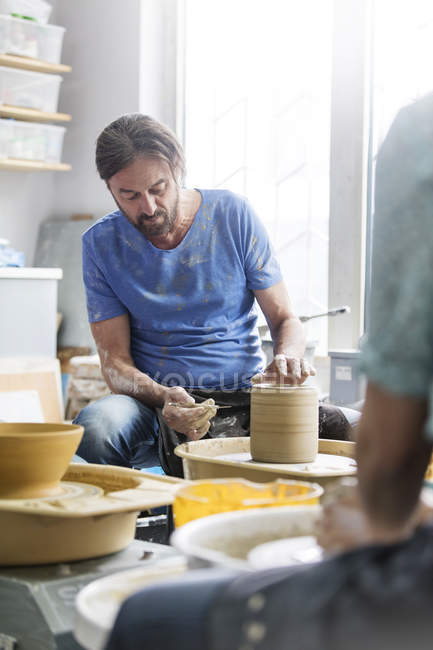 Mature man using pottery wheel in studio — Stock Photo