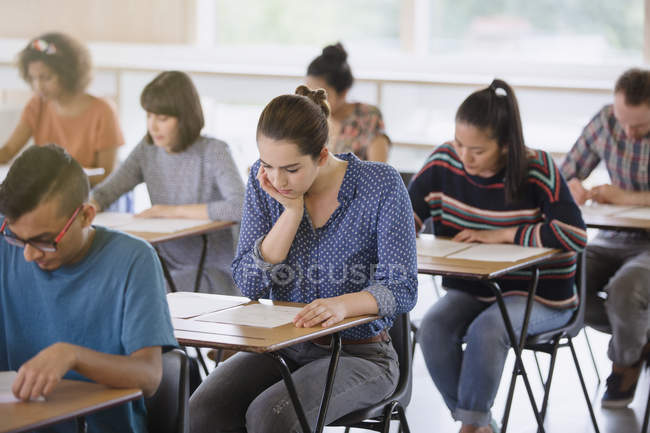 Étudiants de niveau collégial passant le test dans les bureaux en classe — Photo de stock