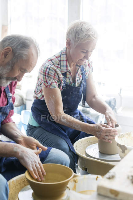 Couple aîné utilisant des roues de poterie en studio — Photo de stock
