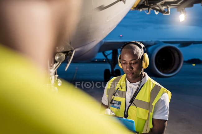 Air traffic control ground crew working under airplane on airport tarmac — Stock Photo